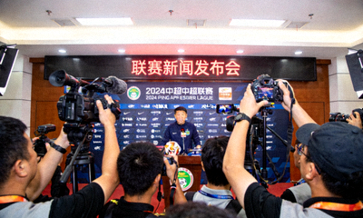 中超联赛官方发布会现场，主教练在讲台上接受媒体采访